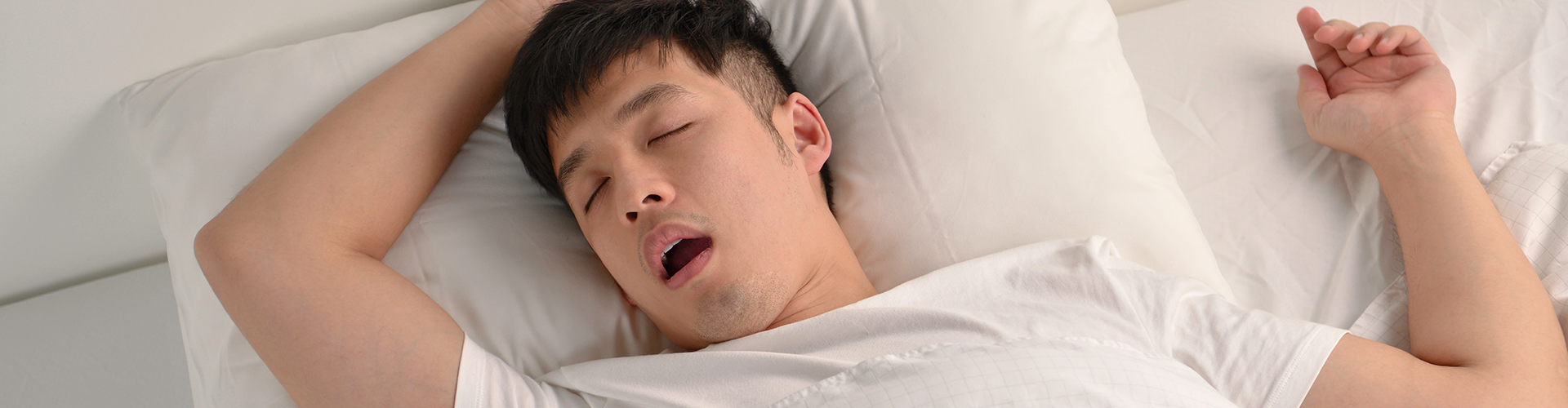 man sleeping on his back in bed